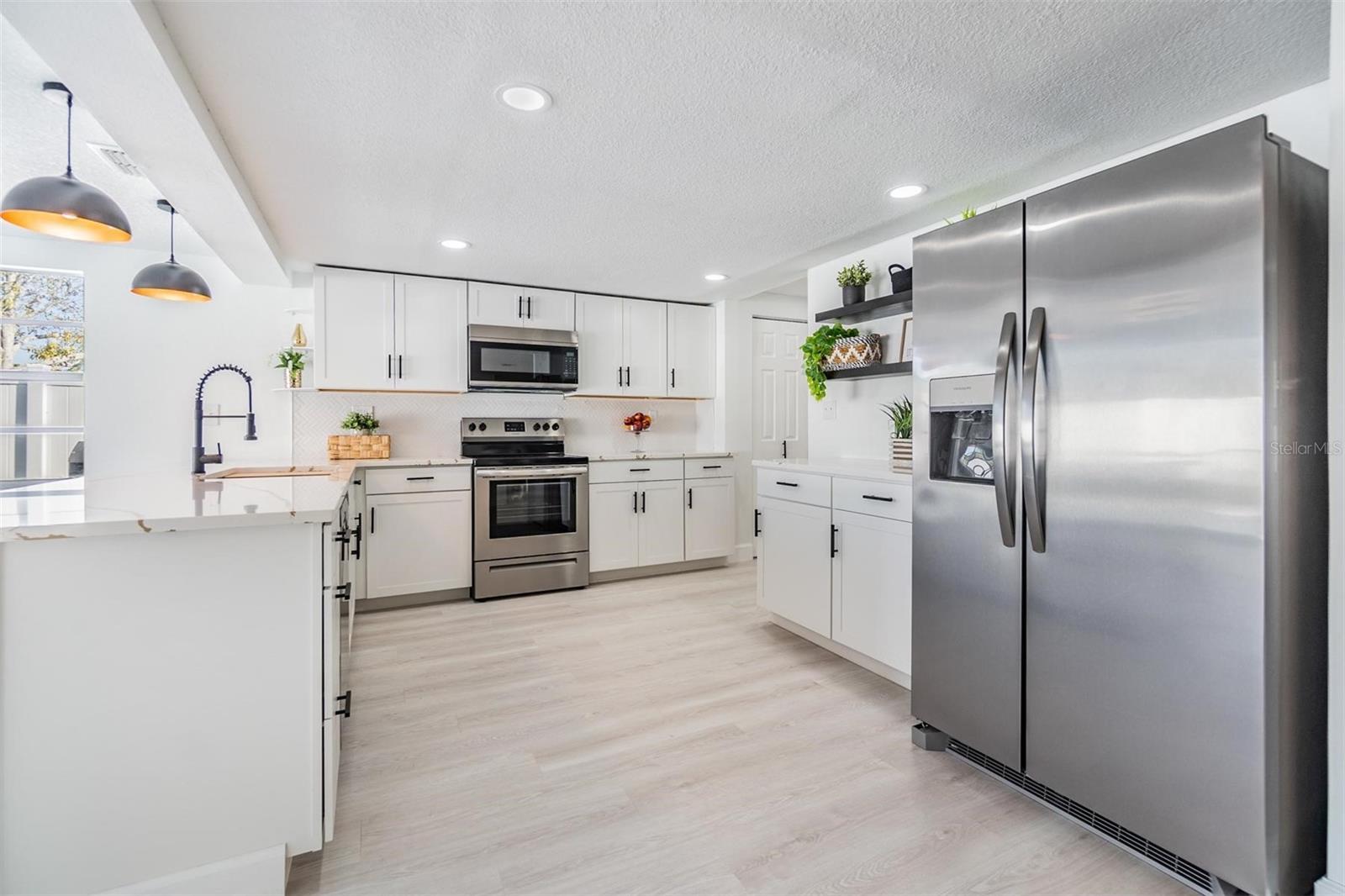 All new renovated kitchen. Luxury vinyl plank flooring, commercial faucet, gourmet sink, quartz countertops, shaker cabinets, stylish shelving, new hardware, can lights and pendulum lights above 10-feet bar.