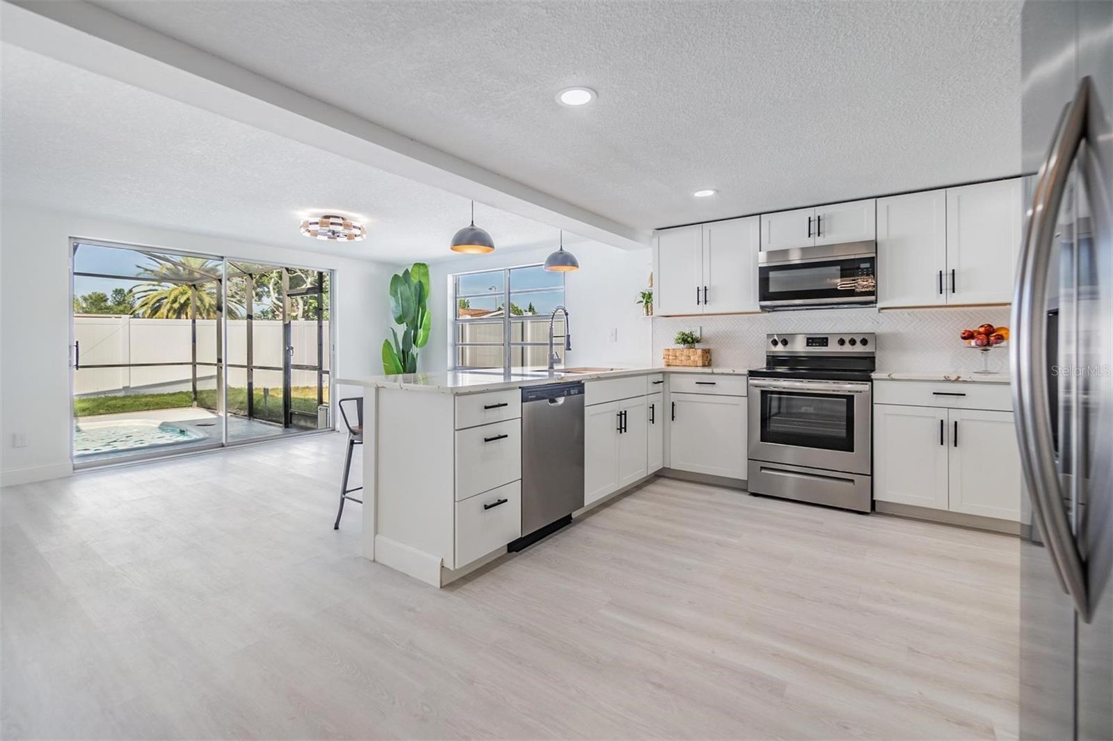 All new renovated kitchen. Luxury vinyl plank flooring, commercial faucet, gourmet sink, quartz countertops, shaker cabinets, stylish shelving, new hardware, can lights and pendulum lights above 10-feet bar.  Window and 2 sliders for entry to the patio/pool area