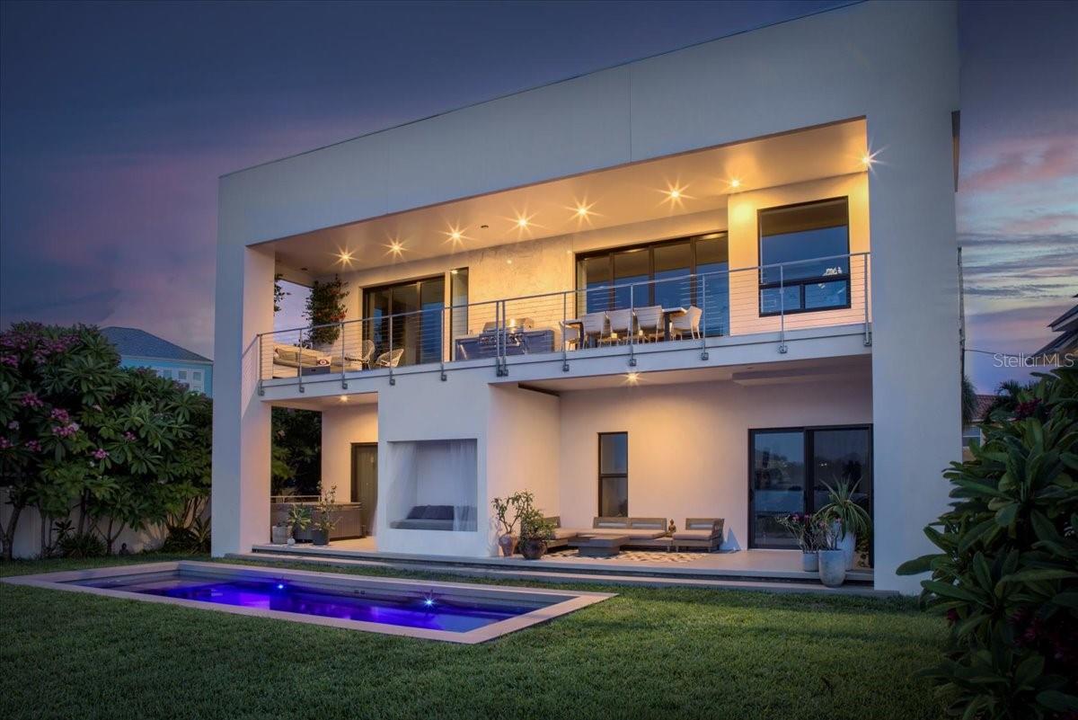 Illuminated rear evening views exhibit the uncommon contemporary presence of this posh, exhilarating residence.