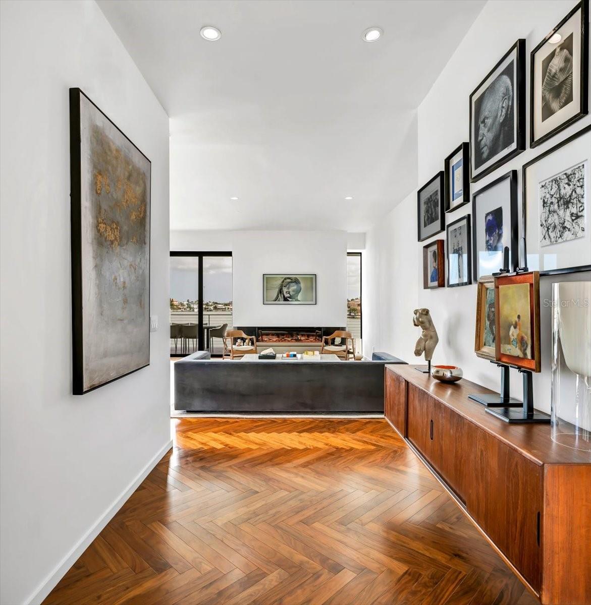 Note the meticulously laid herringbone-pattern wood flooring and perfectly matching credenza of this transitional area, calling you, welcoming you, to a home of soothing character and substance
