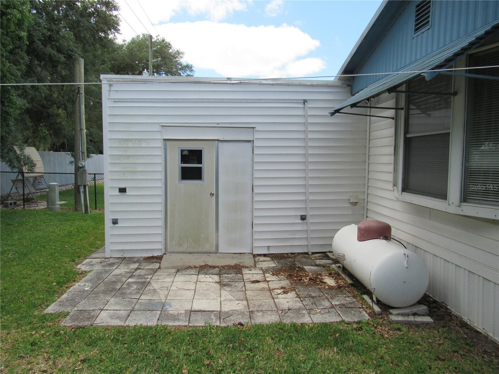 Paver patio & attached utility room with double door for golf cart parking.