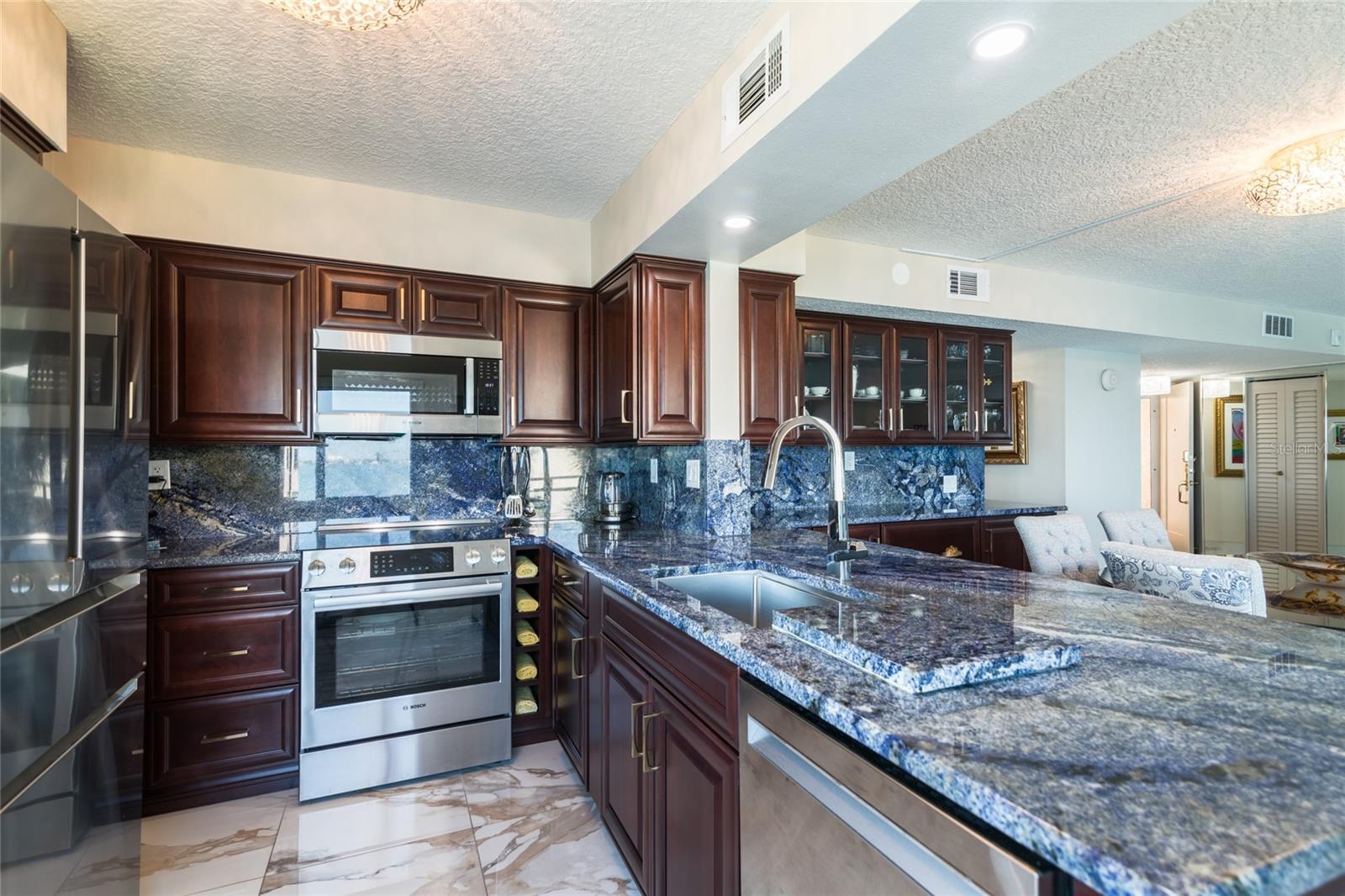 The kitchen has stainless appliances, blue granite countertops, and custom cabinets
