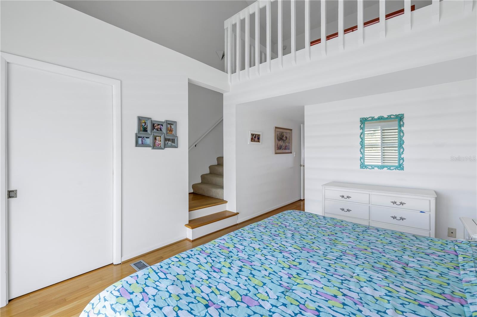 Primary bedroom with wood floors, second loft overlooks the bedroom