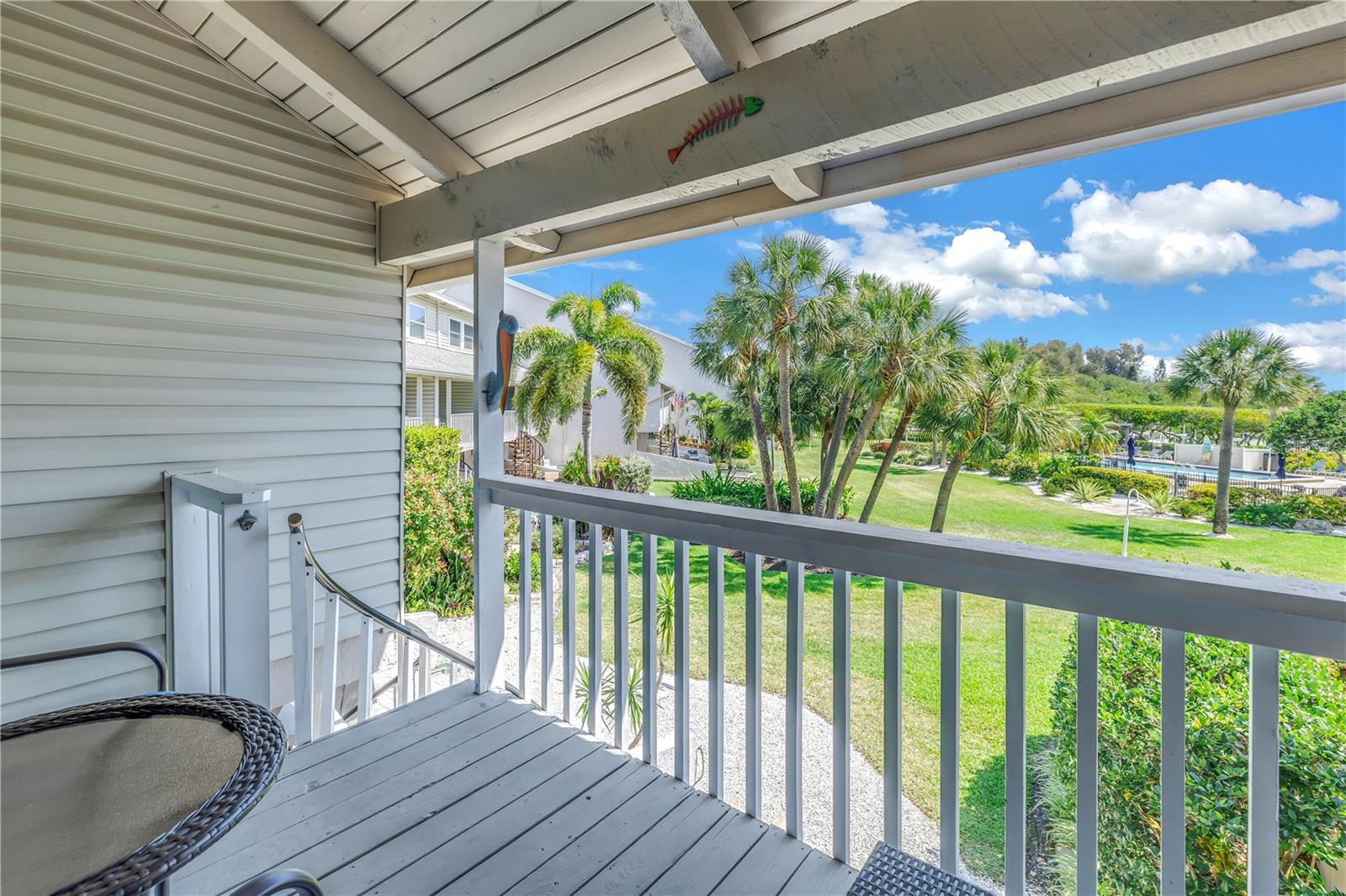 Balcony off the living room with view of  the tropically landscaped yard