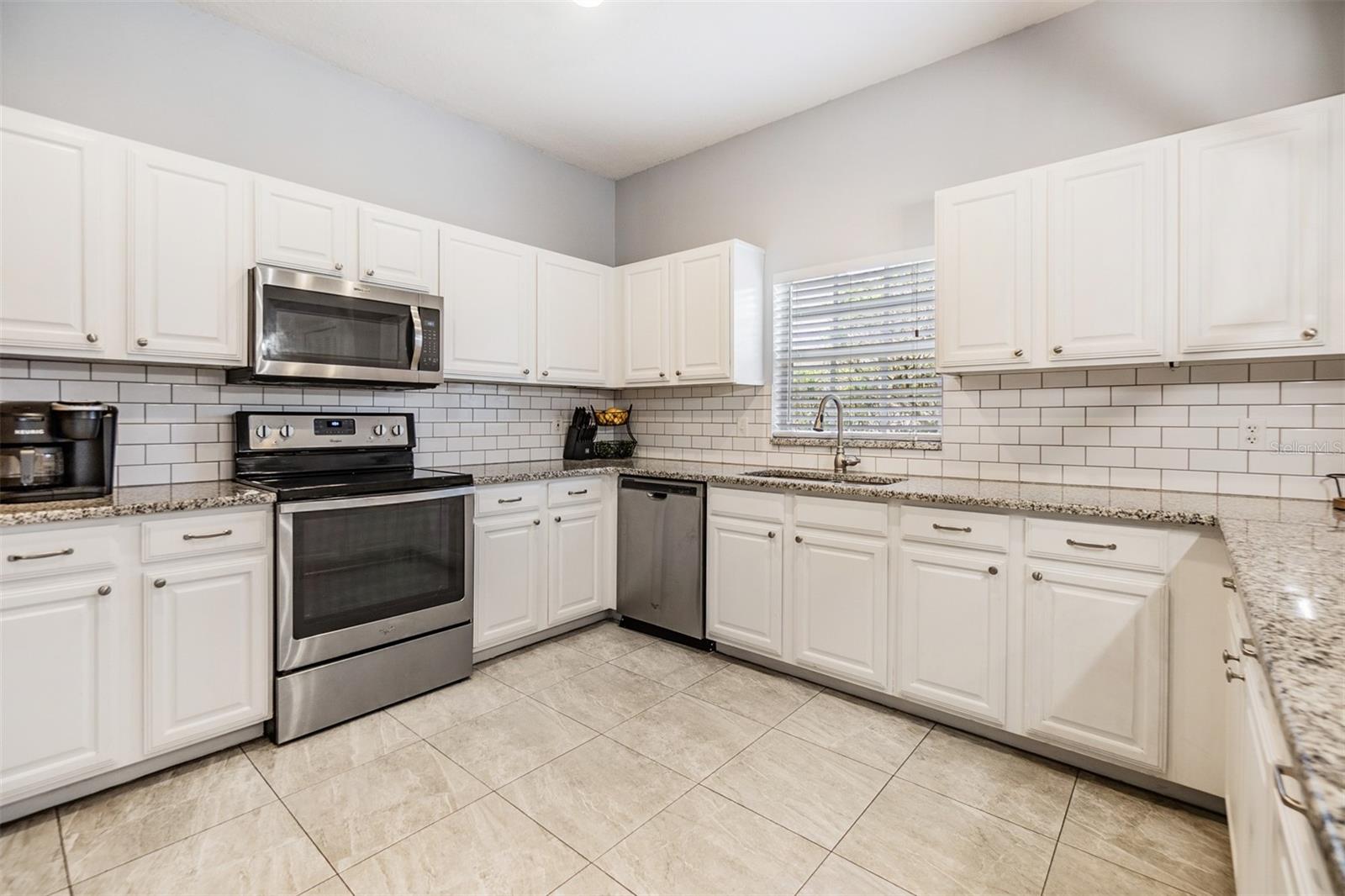 Large and Open kitchen with new light fixture, Subway tile backsplash, Granite Countertops, and Stainless Steel appliances.