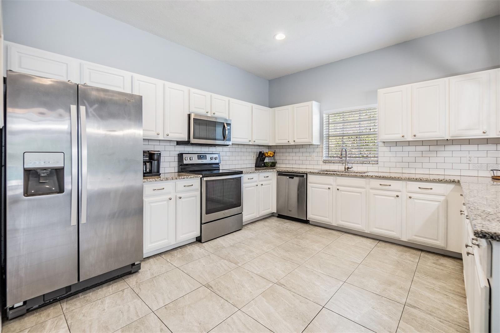 Large and Open kitchen with new light fixture, inset lighting,  Subway tile backsplash, Granite Countertops, and Stainless Steel appliances.