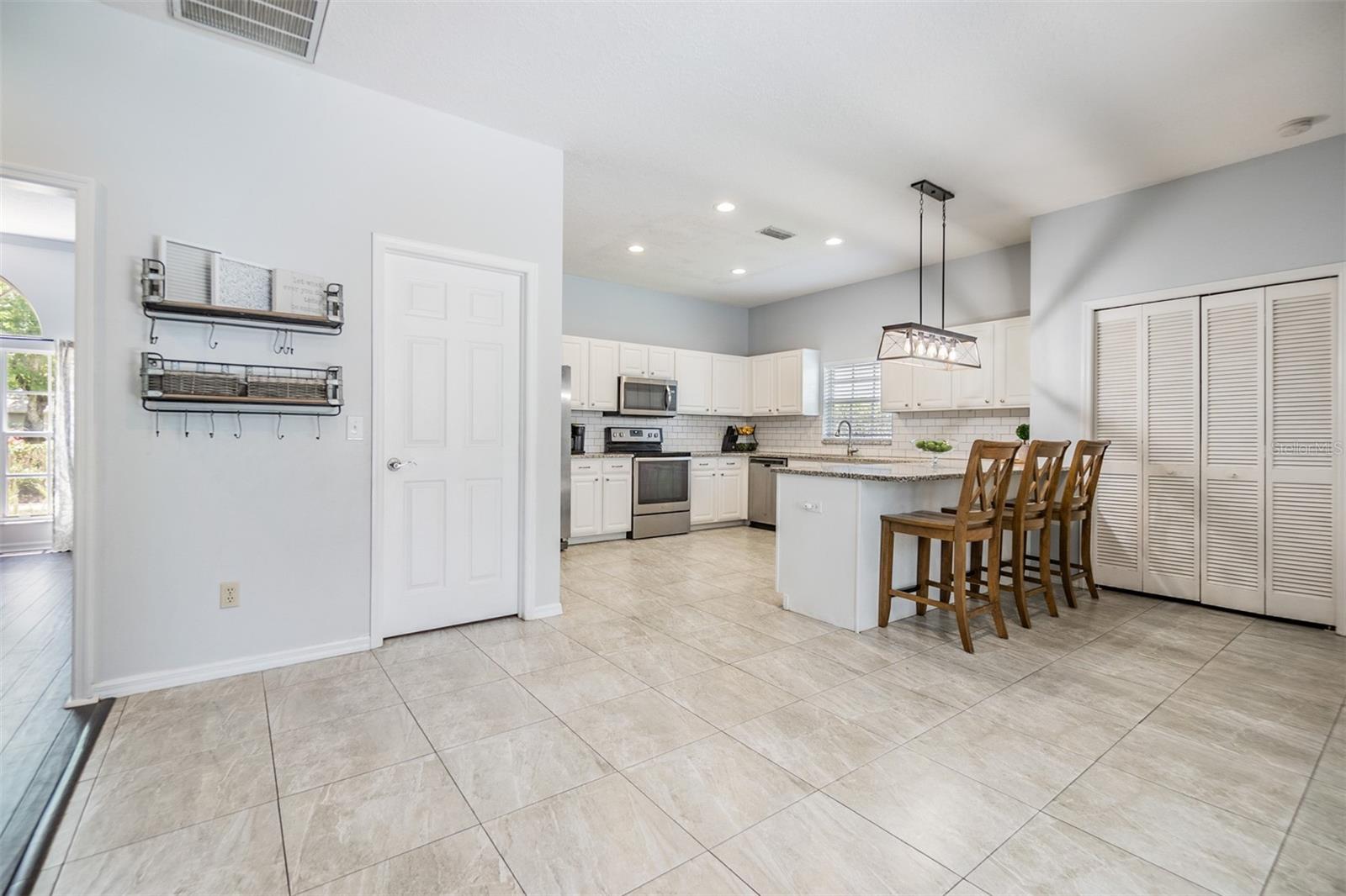 Large and Open kitchen with new light fixture, inset lighting, Subway tile backsplash, Granite Countertops, and Stainless Steel appliances.