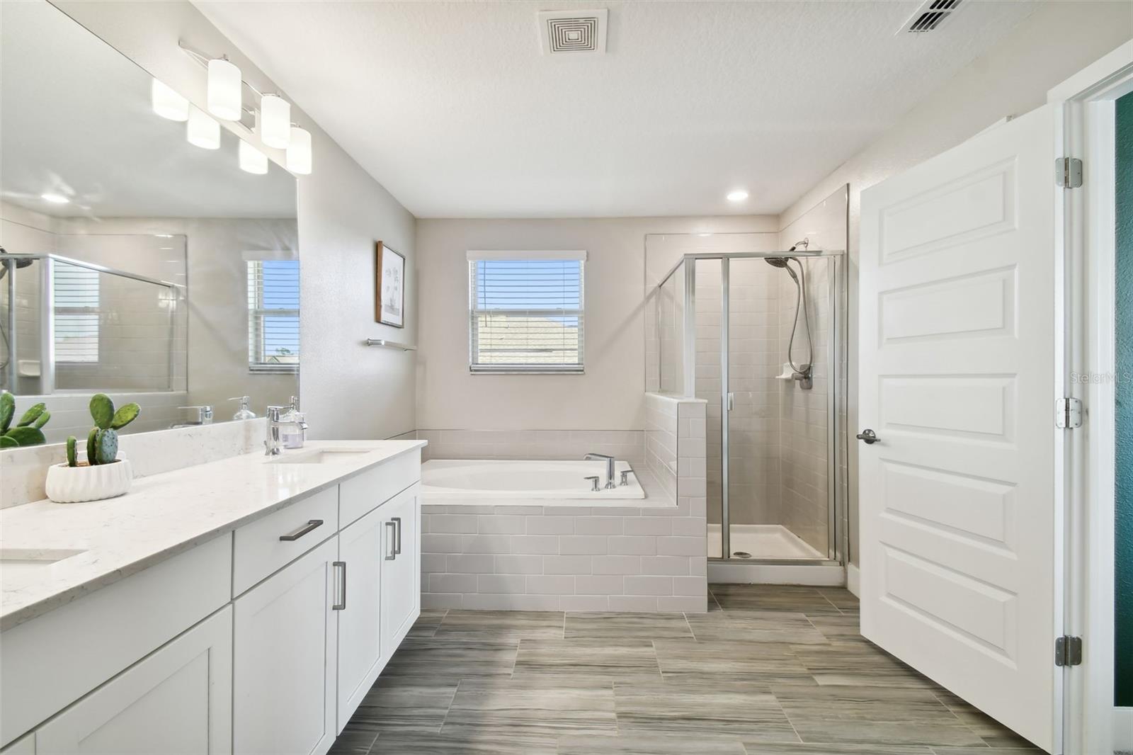 Master bathroom with double sinks, shower, and soaker tub