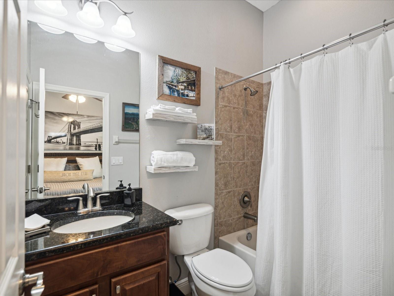 The bathroom features a bathtub/shower combination and granite countertop with a cherry cabinet for storage.