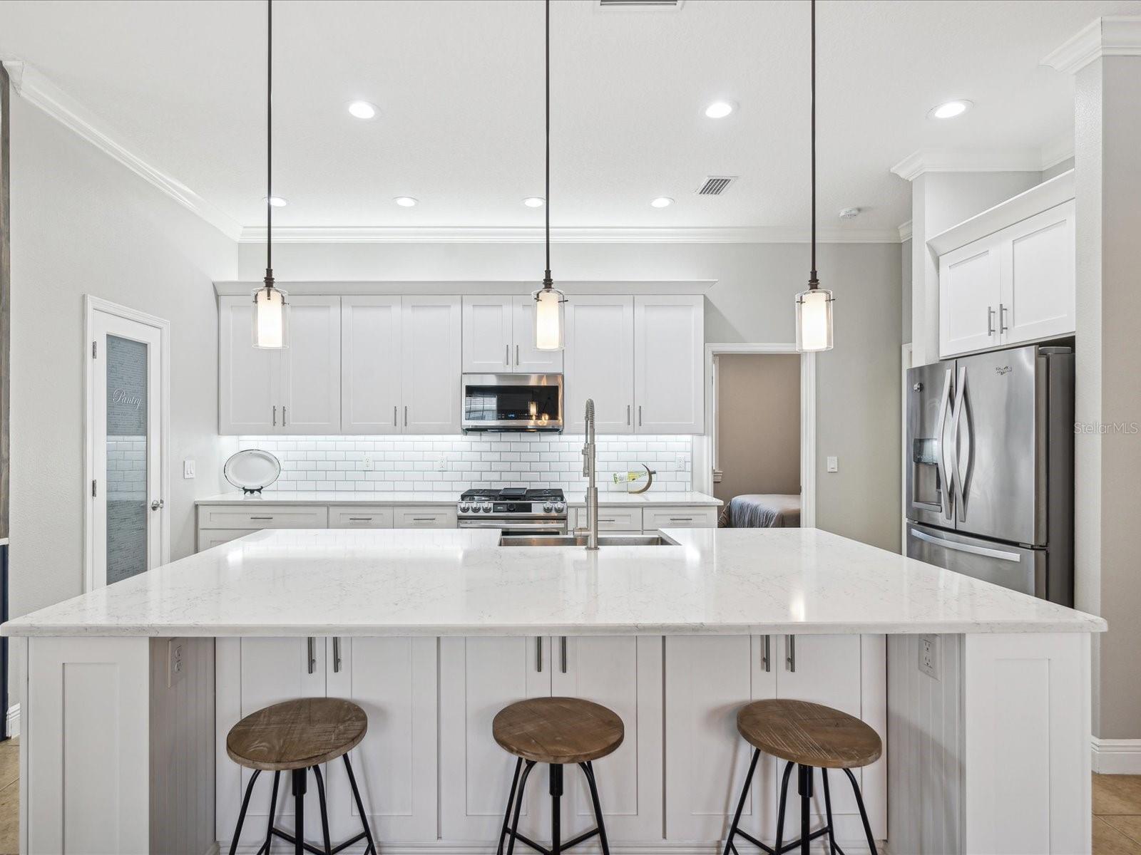 The extra large kitchen island is the focal point of the kitchen. The cabinets and quartz countertops can be used for prep, dining, or serving.