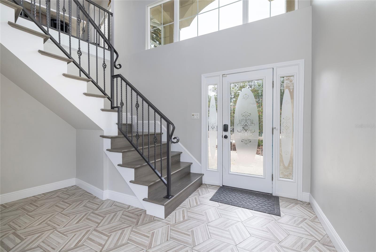 Entrance with beautiful tiled flooring and newly remodeled staircase