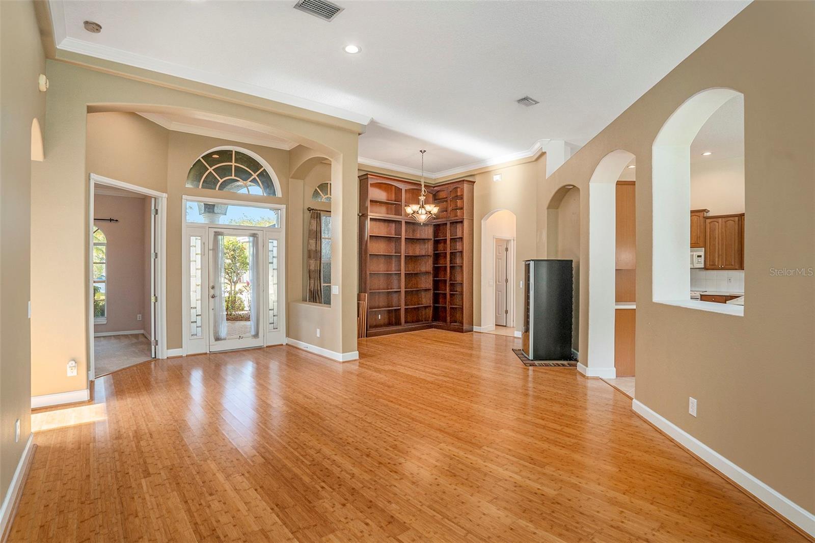Built-in bookshelves. The open space is adorned with archways, columns, and crown molding.