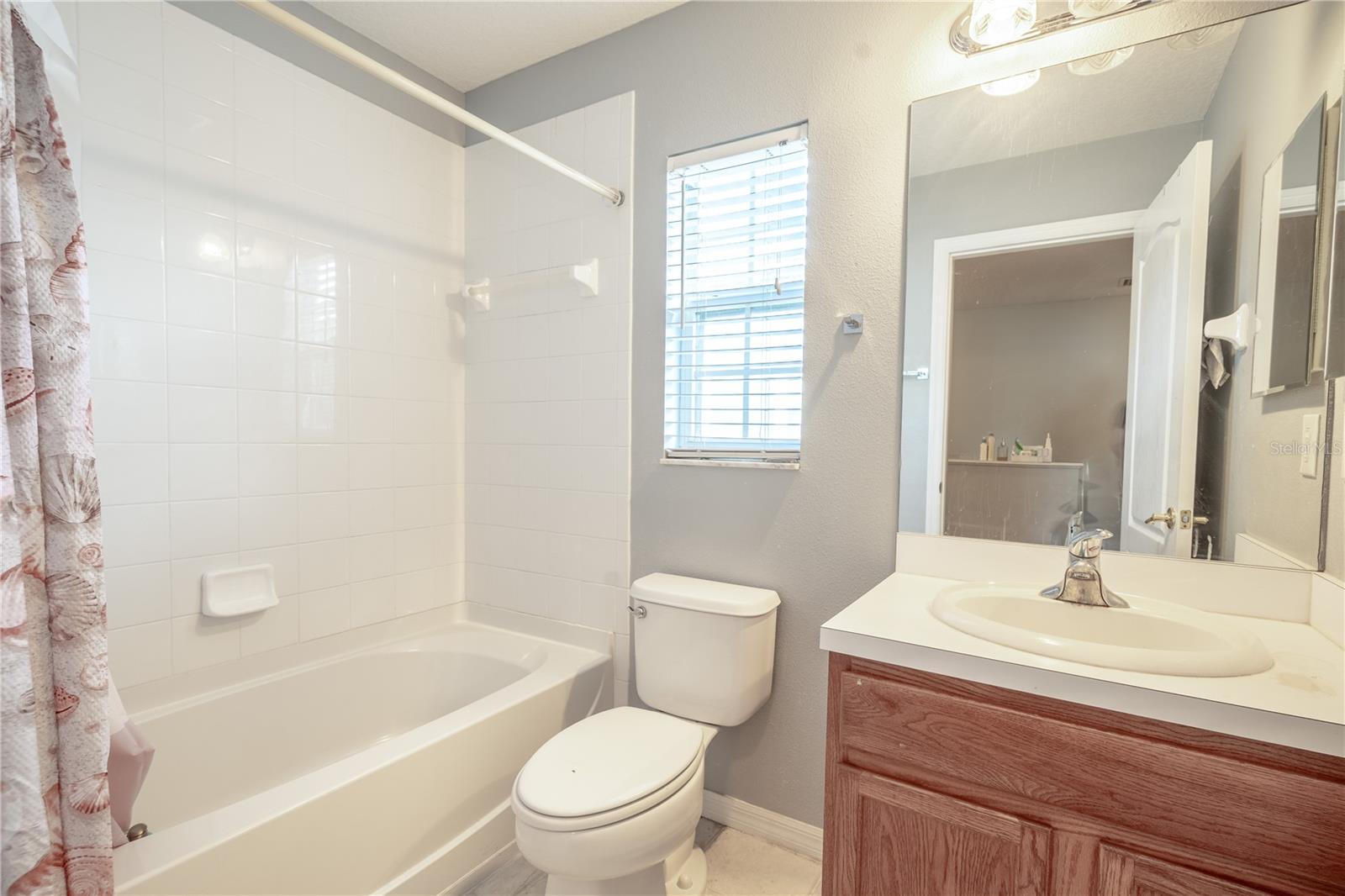 Bathroom 2 features a tub with shower, ceramic tile flooring, and a mirrored vanity with storage.