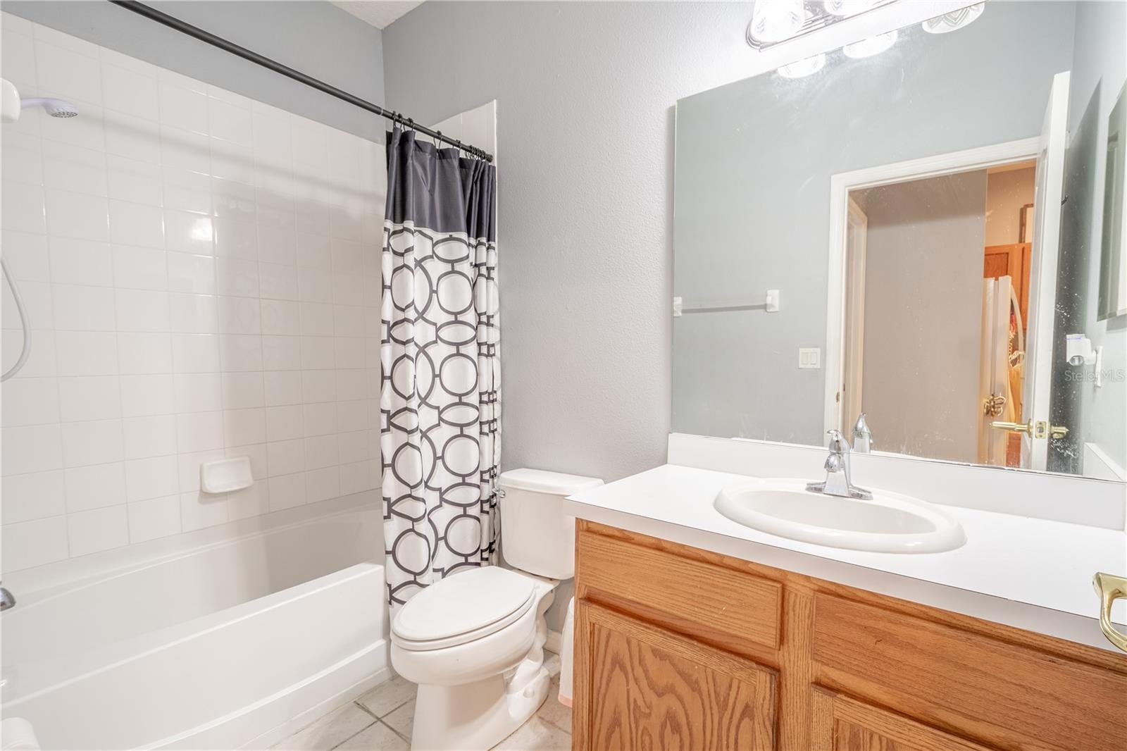 Bathroom 3 is on the first floor. It has ceramic tile flooring, a tub with shower, and a mirrored vanity with storage.