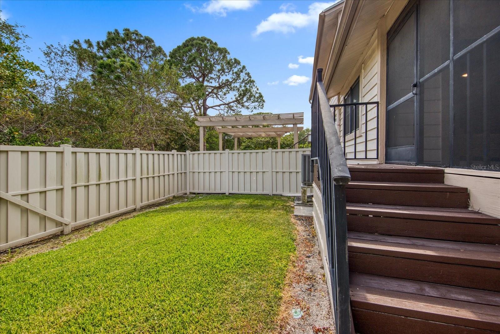 Private fenced in backyard with steps down from the screened in deck.