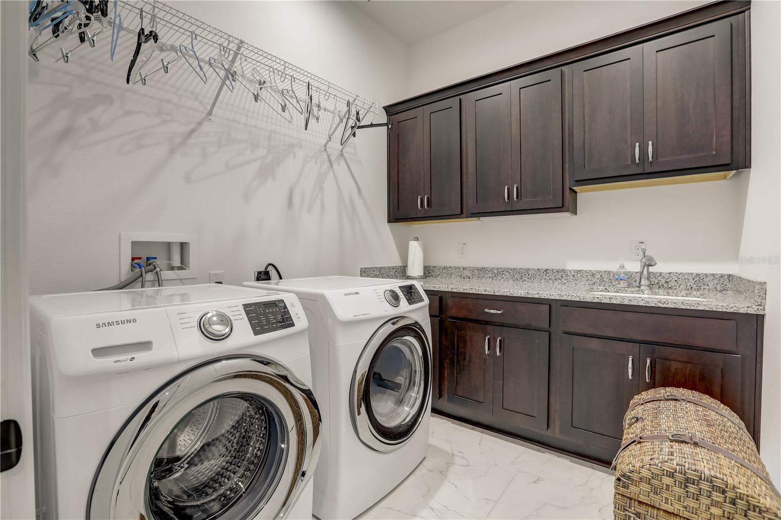 Large laundry room with sink, cabinets and hanging shelf rack