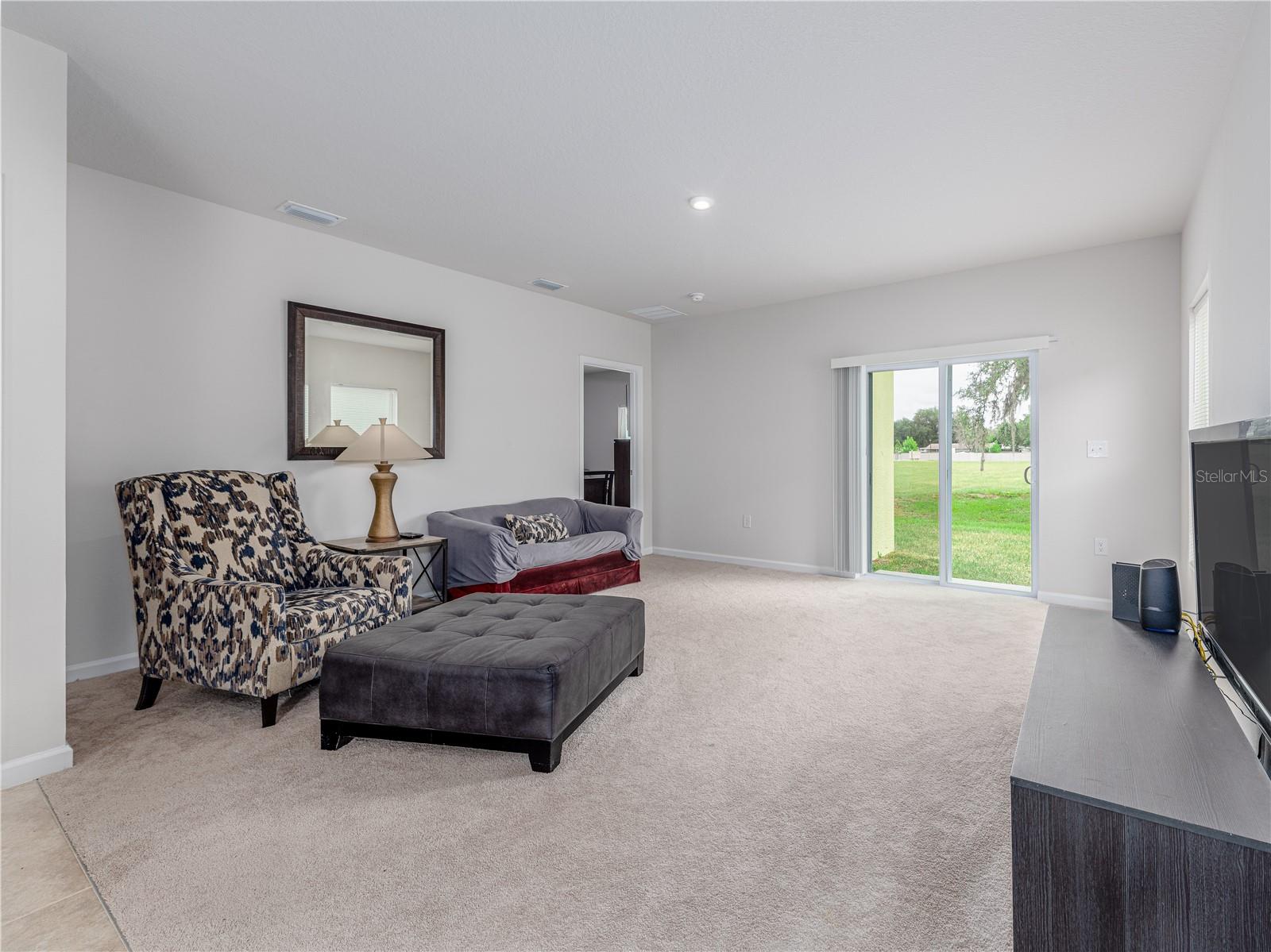 Your spacious living room with sliders leading to green space beyond your back yard.
