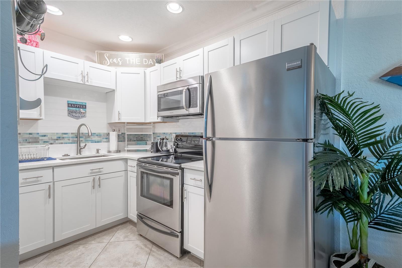 The kitchen features stainless steel appliances, sink  and cabinet pulls for a cohesive look.