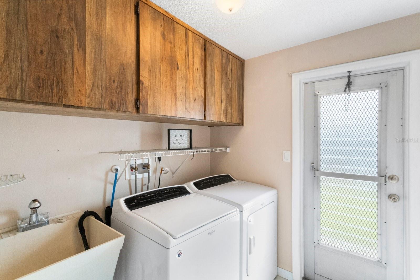 inside laundry room with wash tub and cabinets and door to outside also!