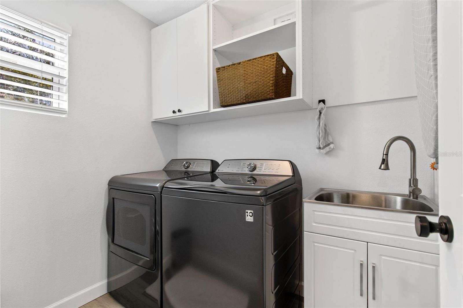 First floor laundry room is equipped with GE washer and dryer units, a sink, and cabinetry for extra convenience.