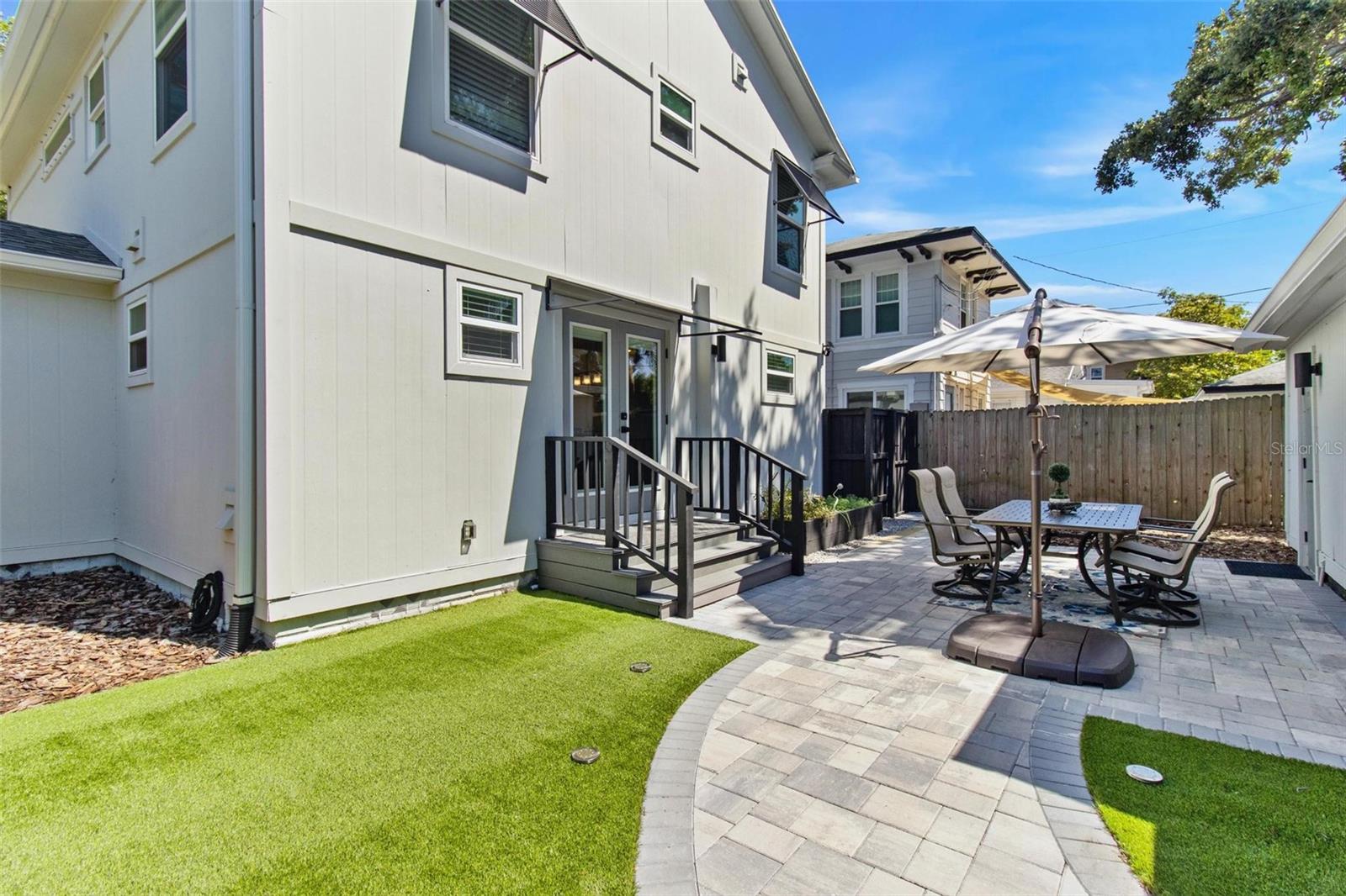 The backyard, between the home and the detached garage, has elegant pavers, artificial turf, raised herbs and vegetable garden, and has ample space to add a pool.