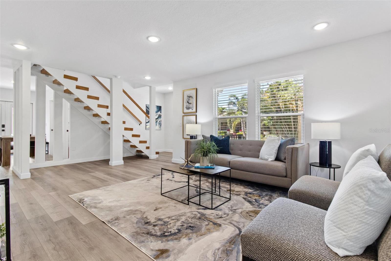 Walk to the open living area, appreciate the floating staircase, luxury vinyl, recessed LED lights and many windows for natural light.