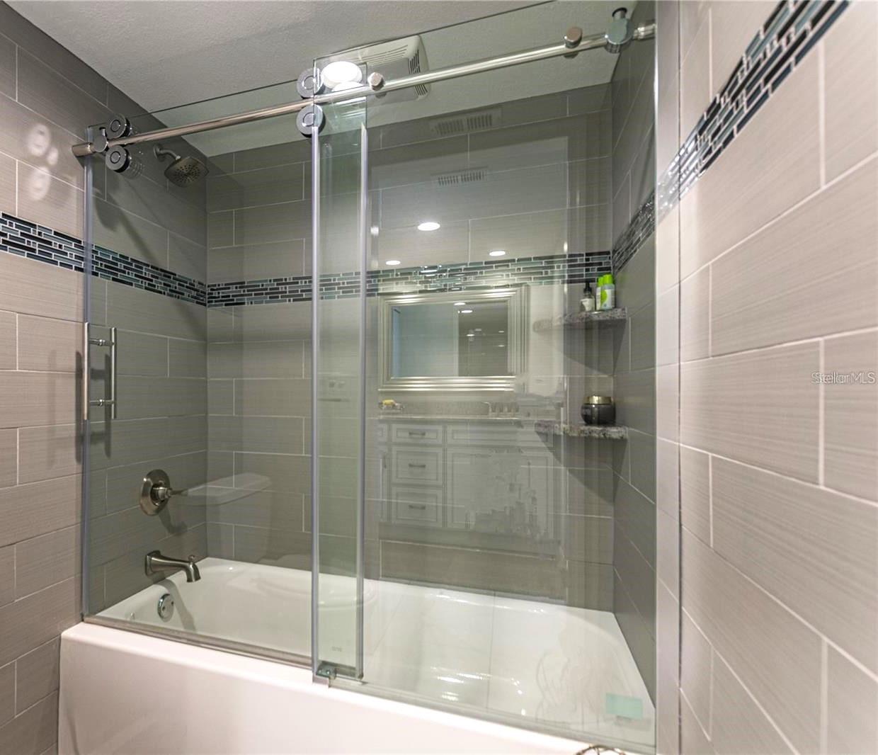 Custom tiled walls and tub with shower, glass sliding doors