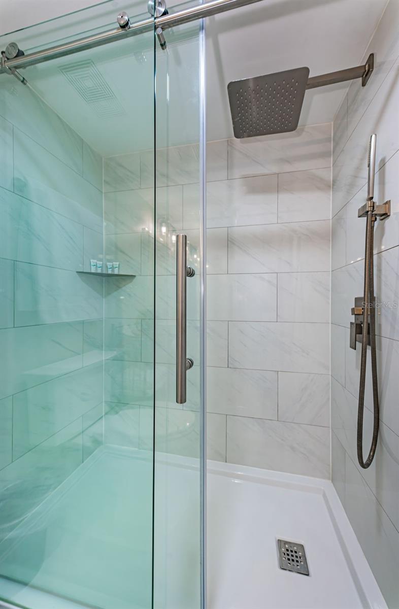 Not only does it feature dual sinks and a glass divider to the shower area, but it also doubles as the laundry area.