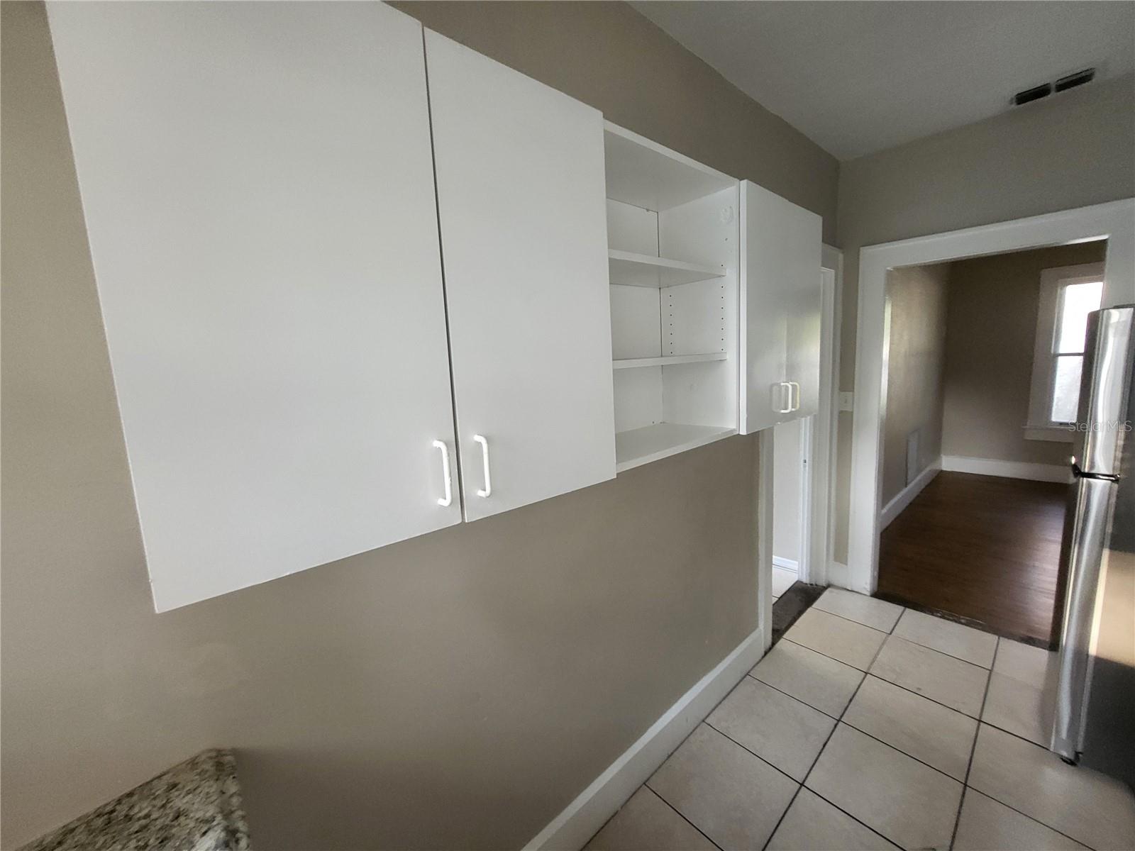 Extra cabinets and open storage on the opposite side of the of the kitchen