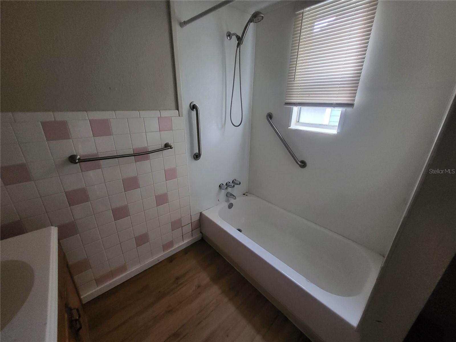 Bathroom has a tub/shower combo and natural light.  Two narrow shelves to the right of the shower for storing linens etc