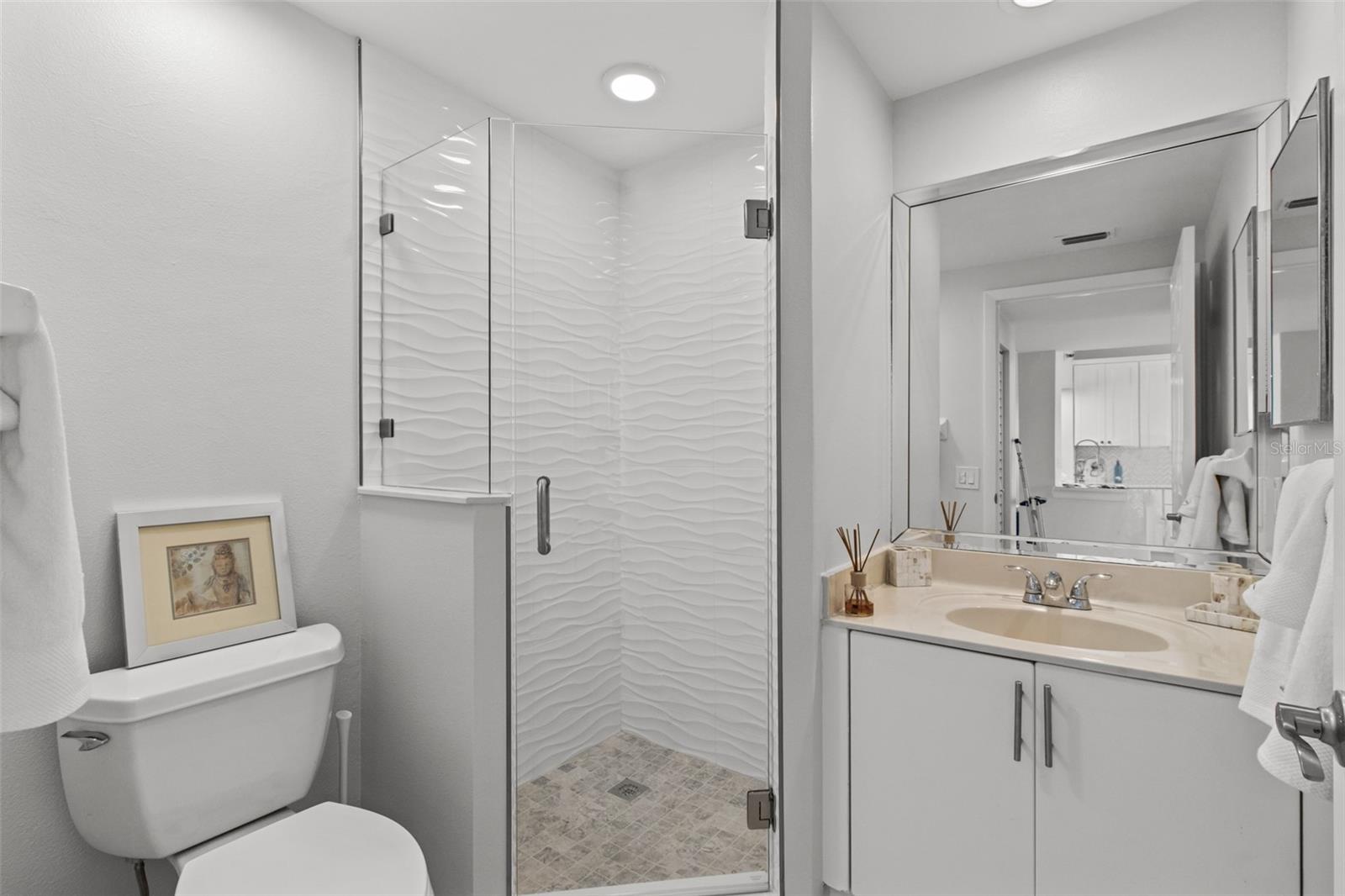 Experience a touch of coastal charm in the newly renovated guest bathroom, featuring elegant coastal tiles and sleek glass shower doors.