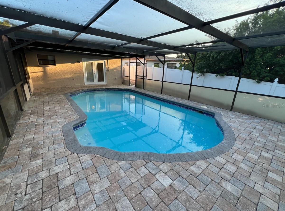 pool with pavered decking and lower privacy screening