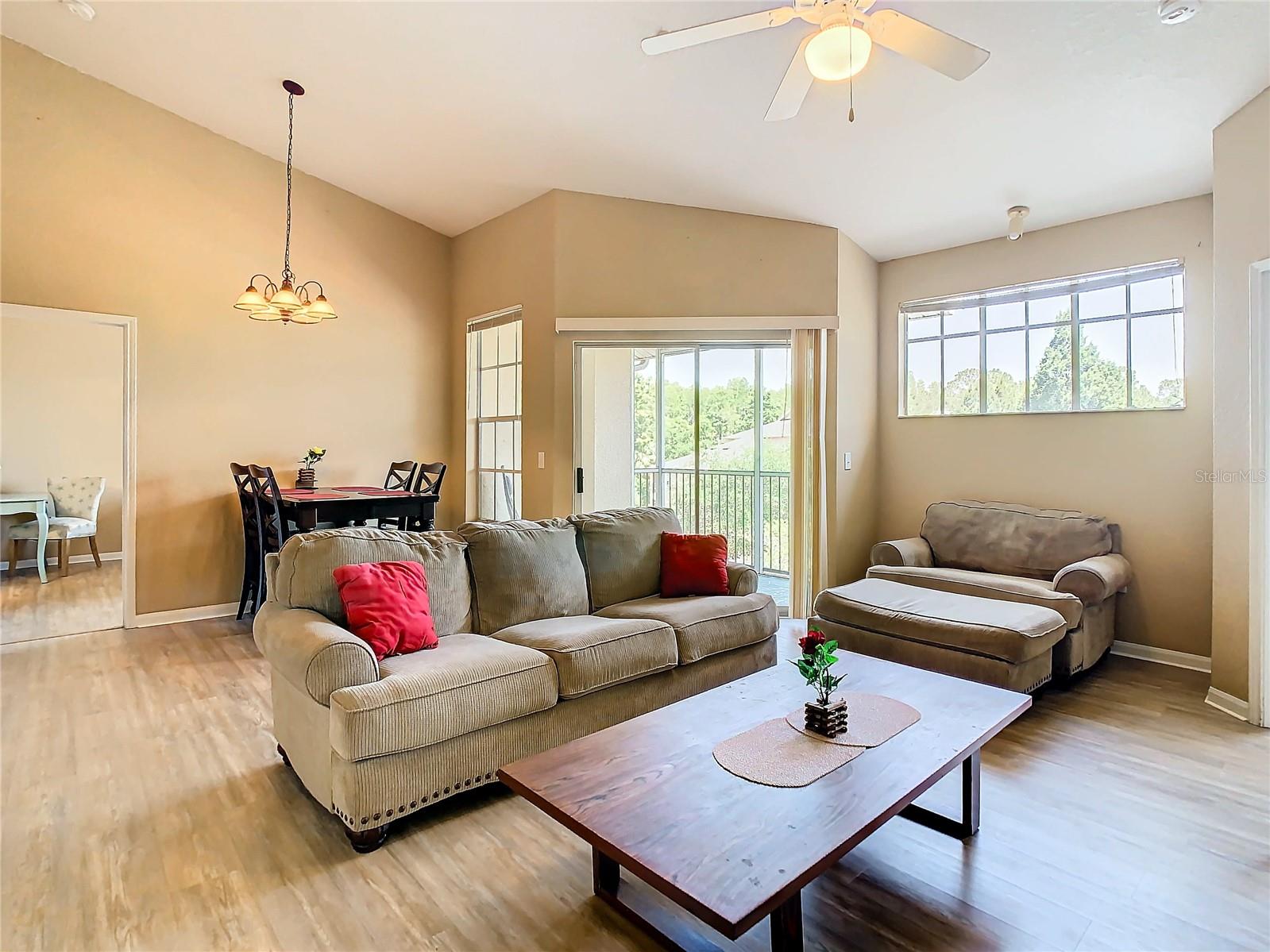 Great room. To the left , out of view, is the kitchen & laundry room. To the right is the entrance to one of the bedrooms with en-suite bath. The opening to the left is the other Primary Bedroom with En-suite Bath. Straight ahead is the screen enclosed patio.