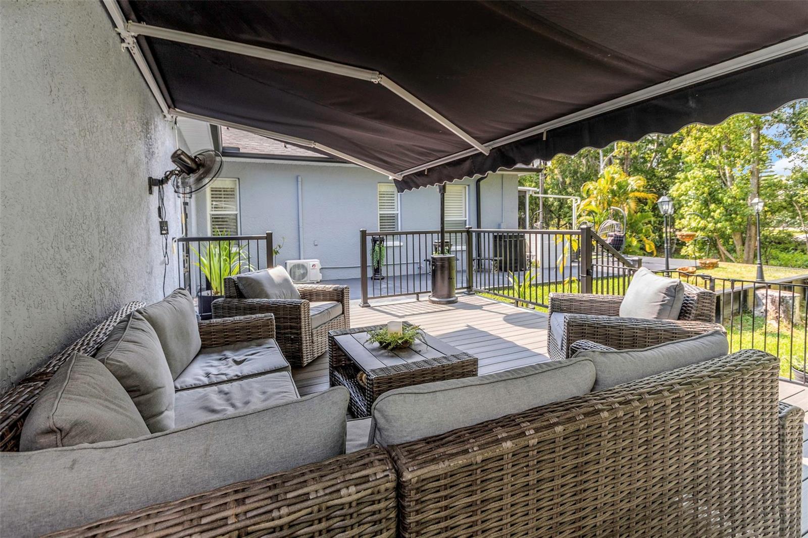 Additional outdoor seating on the smooth surface resin planked deck. Step up to complete privacy and relax in the shade of the motorized retractable awning, cooled by the rotating fans, while looking out over the mountain getaway feel from the lush preserve area that borders the property