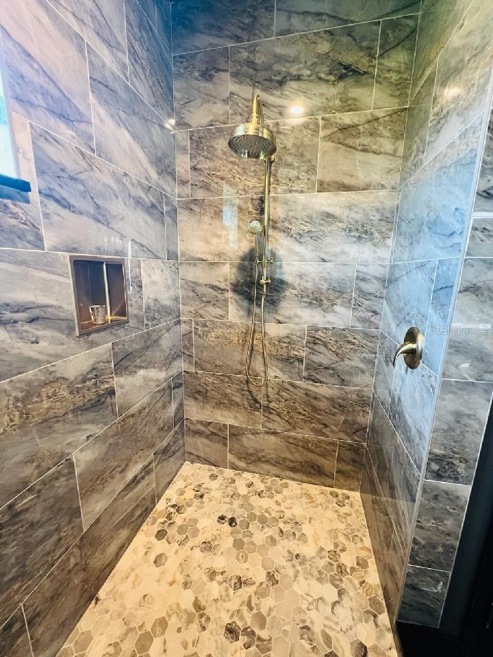 4th bath adjoining the home theater has large Roman Shower with floor to ceiling polished porcelain tile