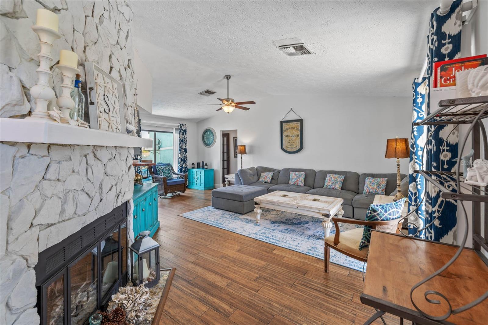 Living room with wood floors and stone fireplace.