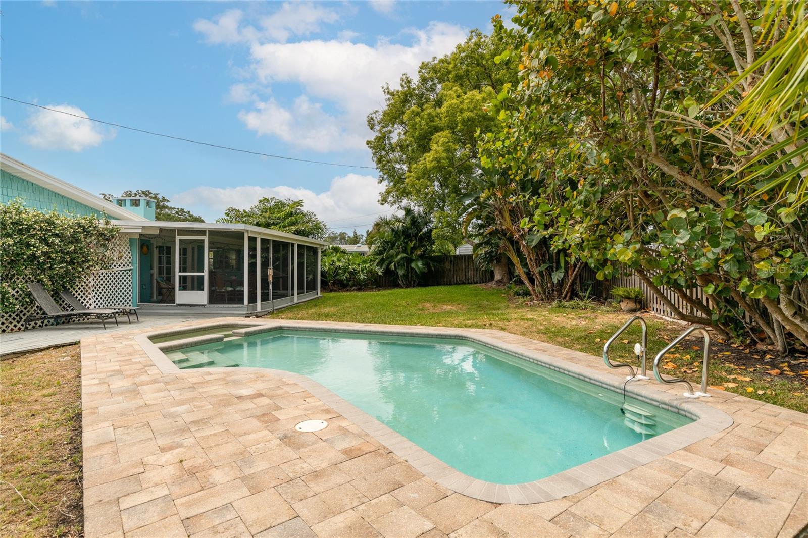 Beautiful inground pool with attached spa and gorgeous paver decking around it.