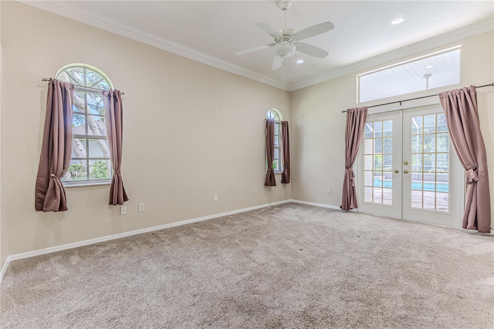 Master Bedroom with Crown Molding, Transom Windows & French Doors out to the Pool Area