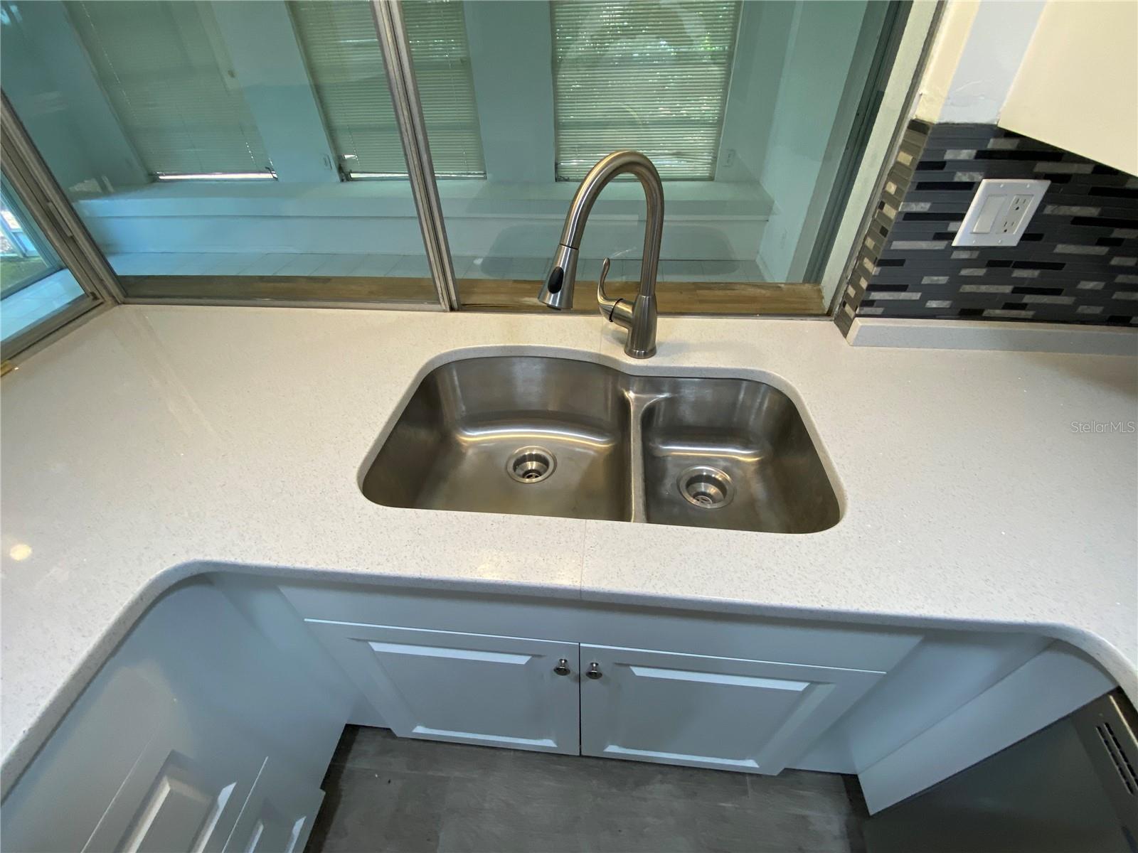 Kitchen sink with enclosed porch beyond it sliding glass window