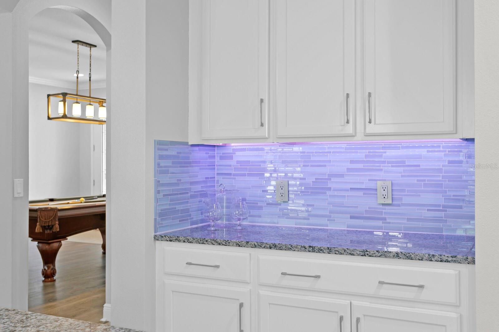 The kichen includes custom glass-tile backsplash and under-cabinet lighting