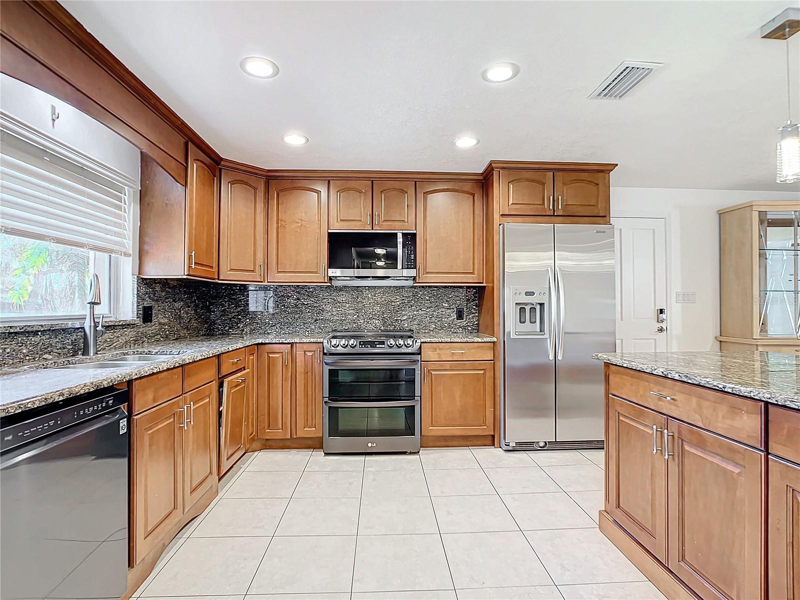 Kitchen double oven flat top cook surface and matching stainless microwave, fridge and diswasher.