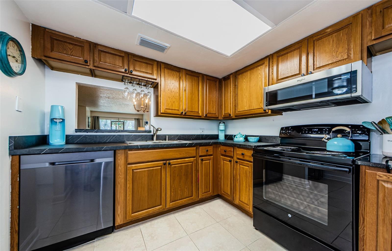 kitchen with ceramic tile, pass through to dining area, double stainless sinks, newer microwave and dishwasher.