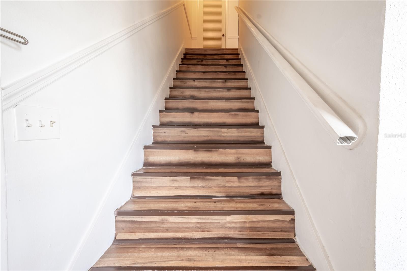 The stairs to the second level are covered in rich wood laminate flooring.