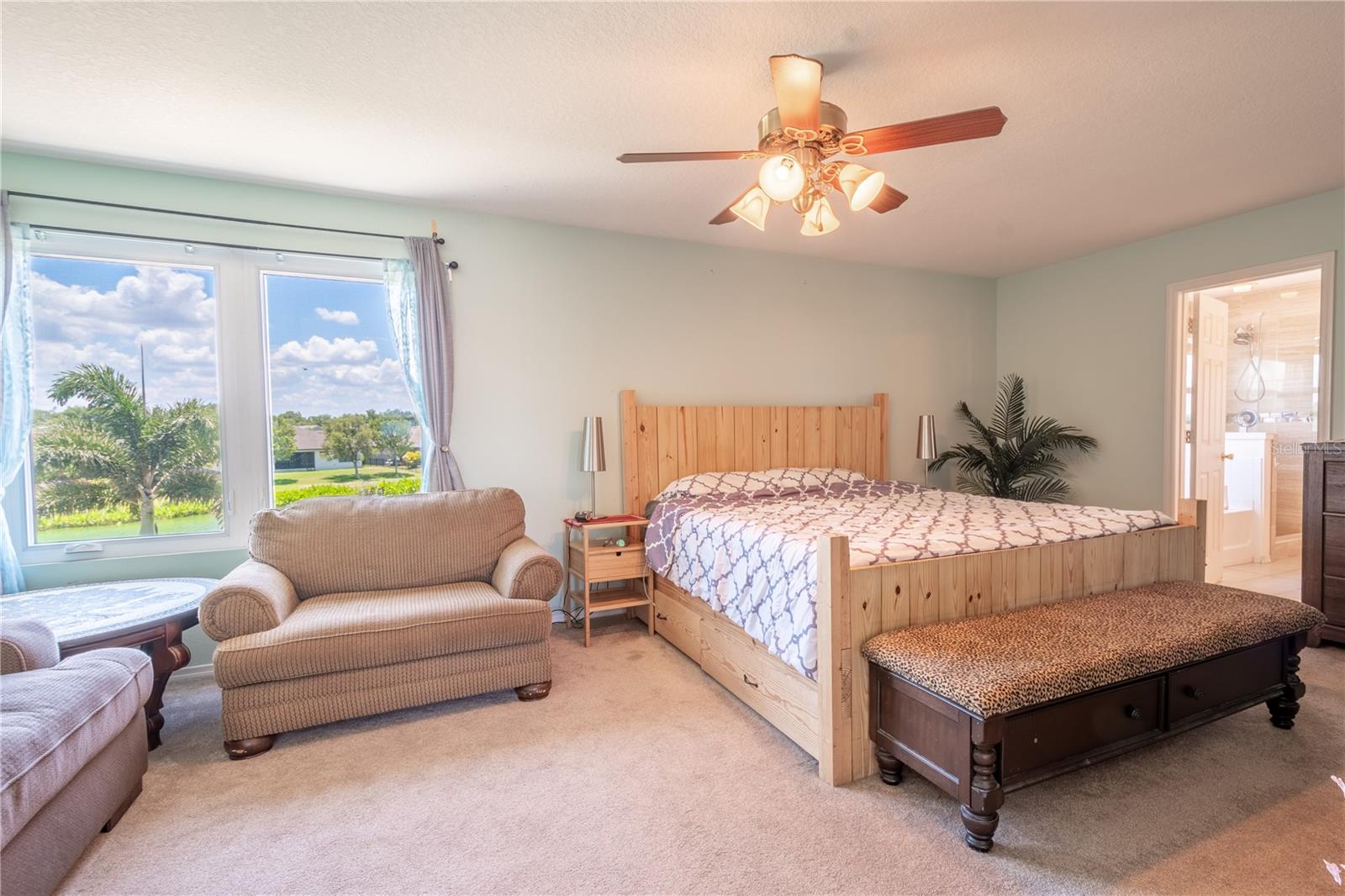 The primary bedroom 13x21  features plush carpet, a ceiling fan with light kit and an ensuite bath.