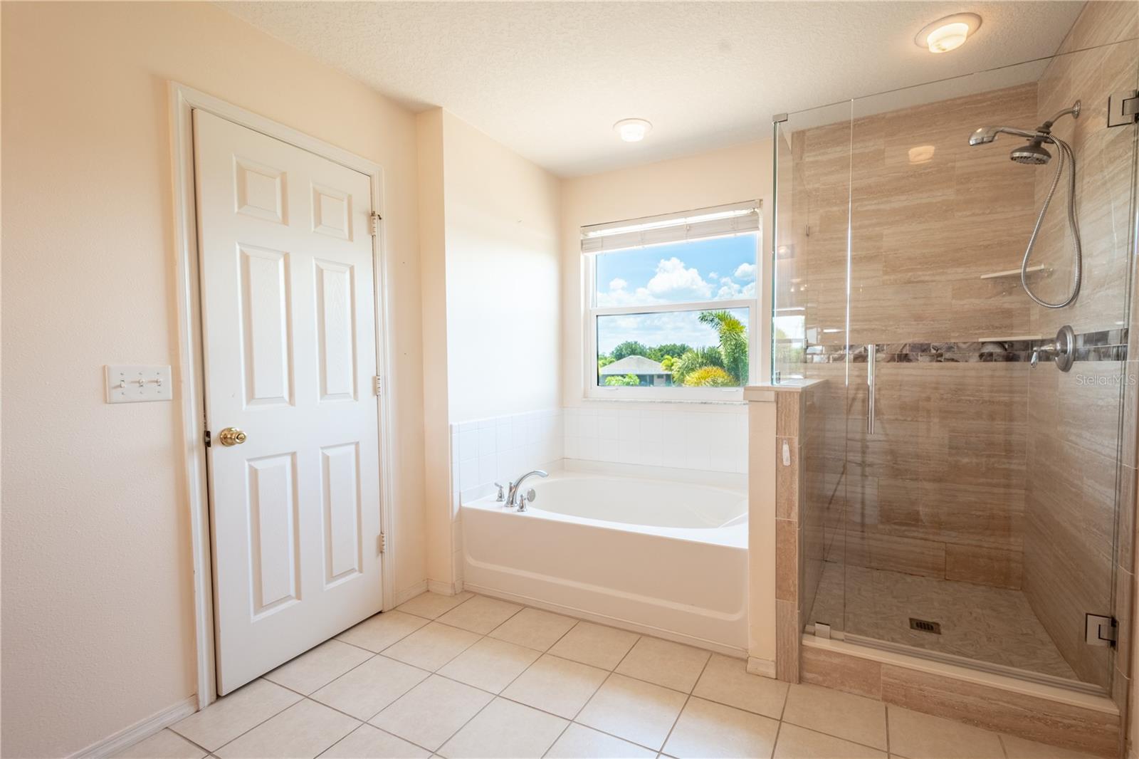 The primary ensuite bath features a tiled, glass enclosed walk-in shower, and a separate bathtub.