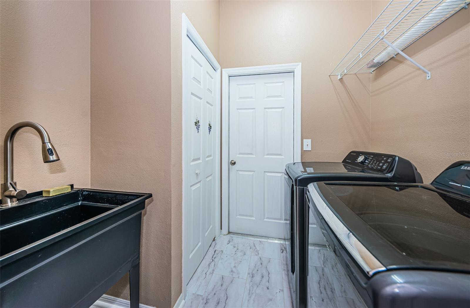 Laundry room with sink, washer and dryer and closet. leads to garage