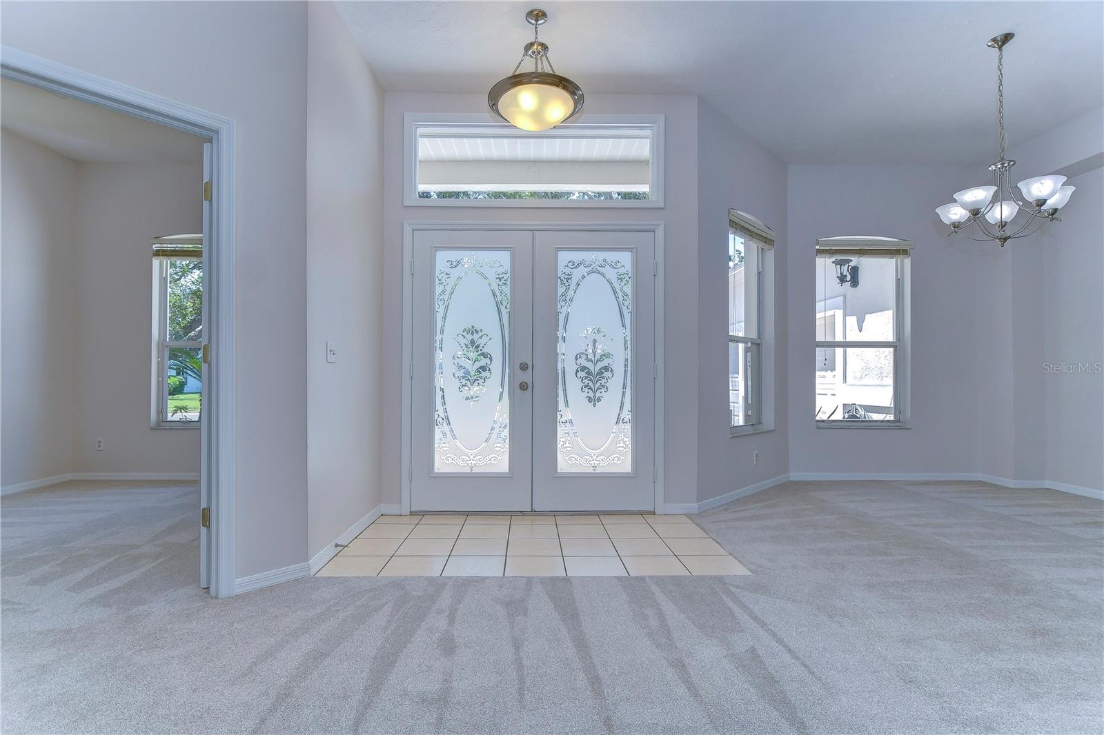 Bright foyer with double decorative glass front doors and a transom window!