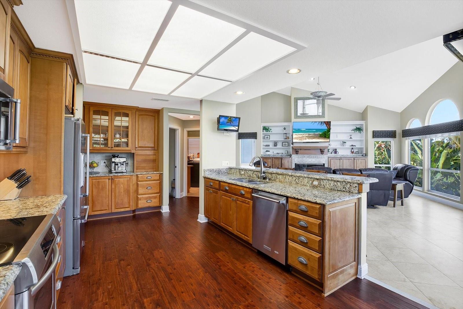 An open kitchen dons wood cabinetry, stainless steel appliances and granite countertops