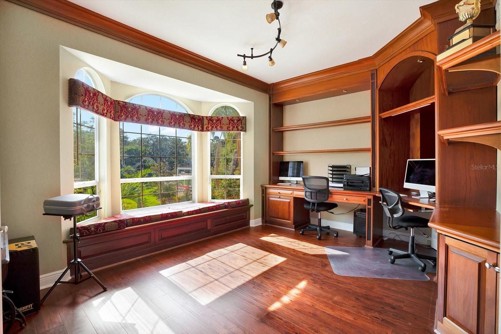 An tasteful office clad in gorgeous wooden built-ins is located right off the formal living room and offers the perfect place to work from home, or a spot in the sun to read your favorite book