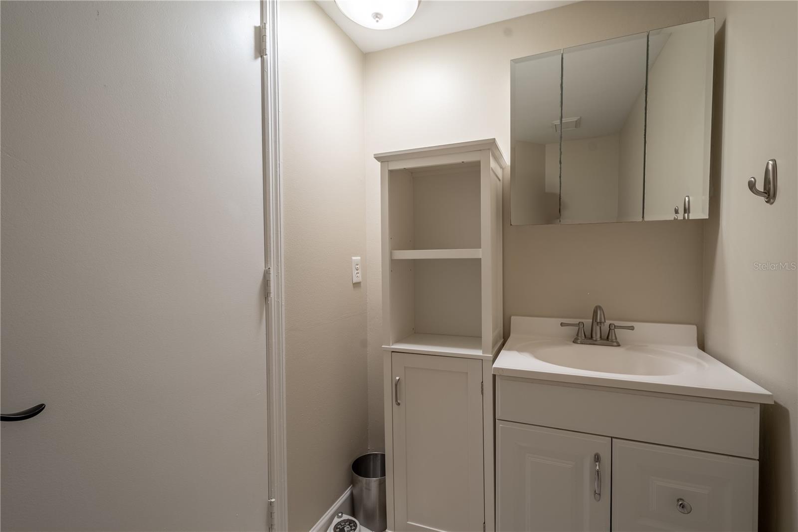 The first floor half bath features a mirrored vanity with storage.